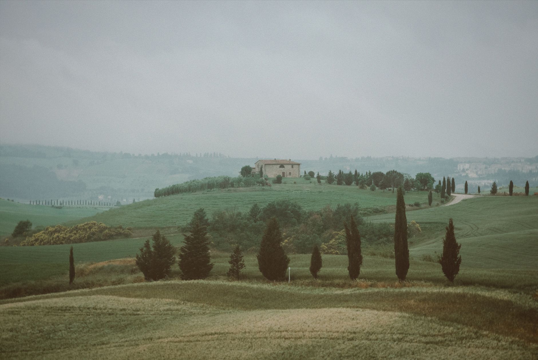 Tuscan stone farmhouse surrounded by rolling hills and cypress trees